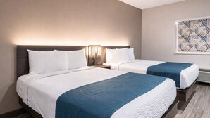 Ein Hotelzimmer mit zwei Betten, jeweils mit weißer Bettwäsche und blauen Akzenten.