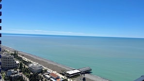 A coastal view with a beach, a round building, and a modern structure with a flat roof. - Panoramic Sea view apartment (Batumi)