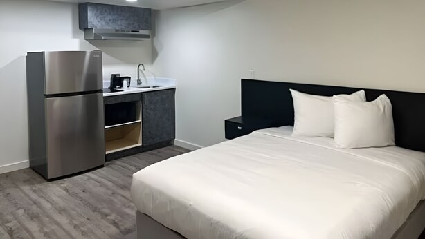 A hotel room with a bed, a kitchenette, and a refrigerator. - Value Stay Near Tri-Cities Airport, Columbia River & Family Adventures (Pasco)