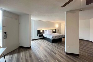 A modern hotel room with a bed, bedside tables, and a ceiling fan. - King Room | Pet-Friendly | 3.4 Miles from Woodland Hills Golf Club (Nacogdoches)