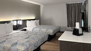 Ein Hotelzimmer mit zwei Betten, einem Schreibtisch und einem Spiegel.