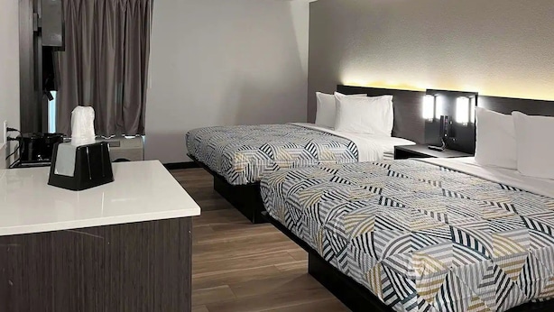 Ein Hotelzimmer mit Bett, Nachttisch und Schreibtisch mit Telefon.