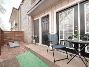 A patio with a table and chairs, a door, and a small garden area.