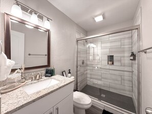 A modern bathroom with a large mirror, a sink, and a shower area.