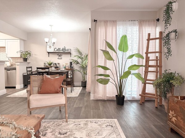 A cozy living room with a wooden coffee table, a sofa, and a dining area with a chandelier.