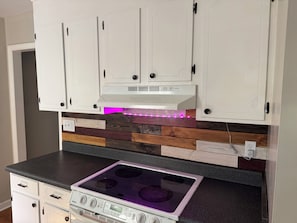 A kitchen with white cabinets, a black countertop, and a stainless steel stove. - Tranquil 3-bedroom house with AC in charming Charlotte (Charlotte)