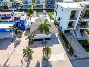 A modern residential area with a pool, palm trees, and a canal. - Vida Isla on Palermo- Heated Pool- Sleeps 10 (Fort Myers Beach)