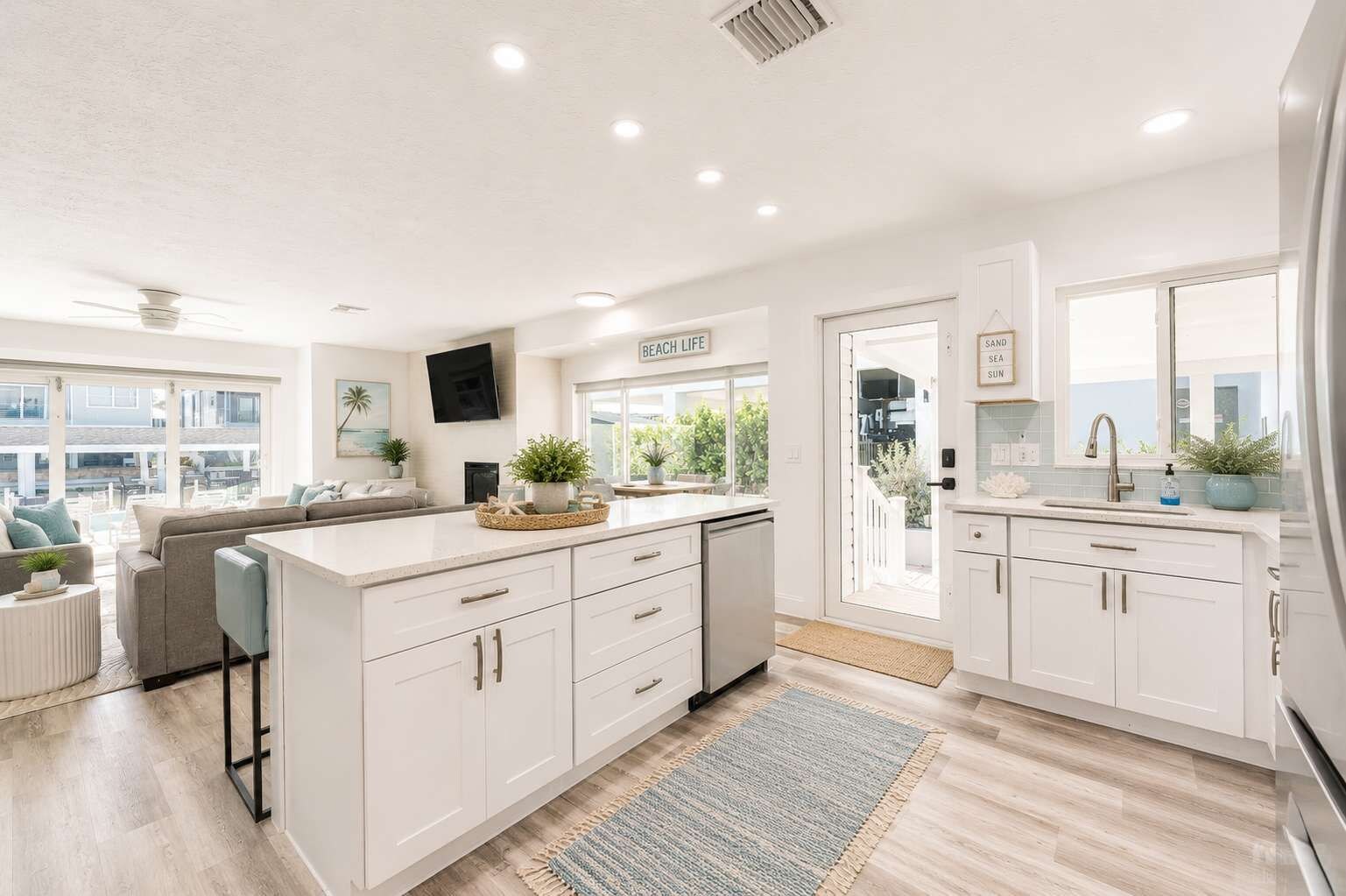 A modern kitchen with white cabinetry, a built-in island, and a view to the outside.