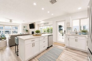 A modern kitchen with white cabinetry, a built-in island, and a view to the outside. - Vida Isla on Palermo- Heated Pool- Sleeps 10 (Fort Myers Beach)
