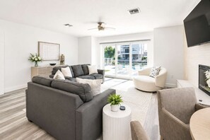Ein modernes Wohnzimmer mit einem grauen Ecksofa, einem weißen Sessel und einem runden Couchtisch.