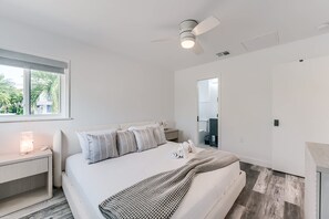Ein modernes Schlafzimmer mit Bett, Nachttisch und Deckenventilator.