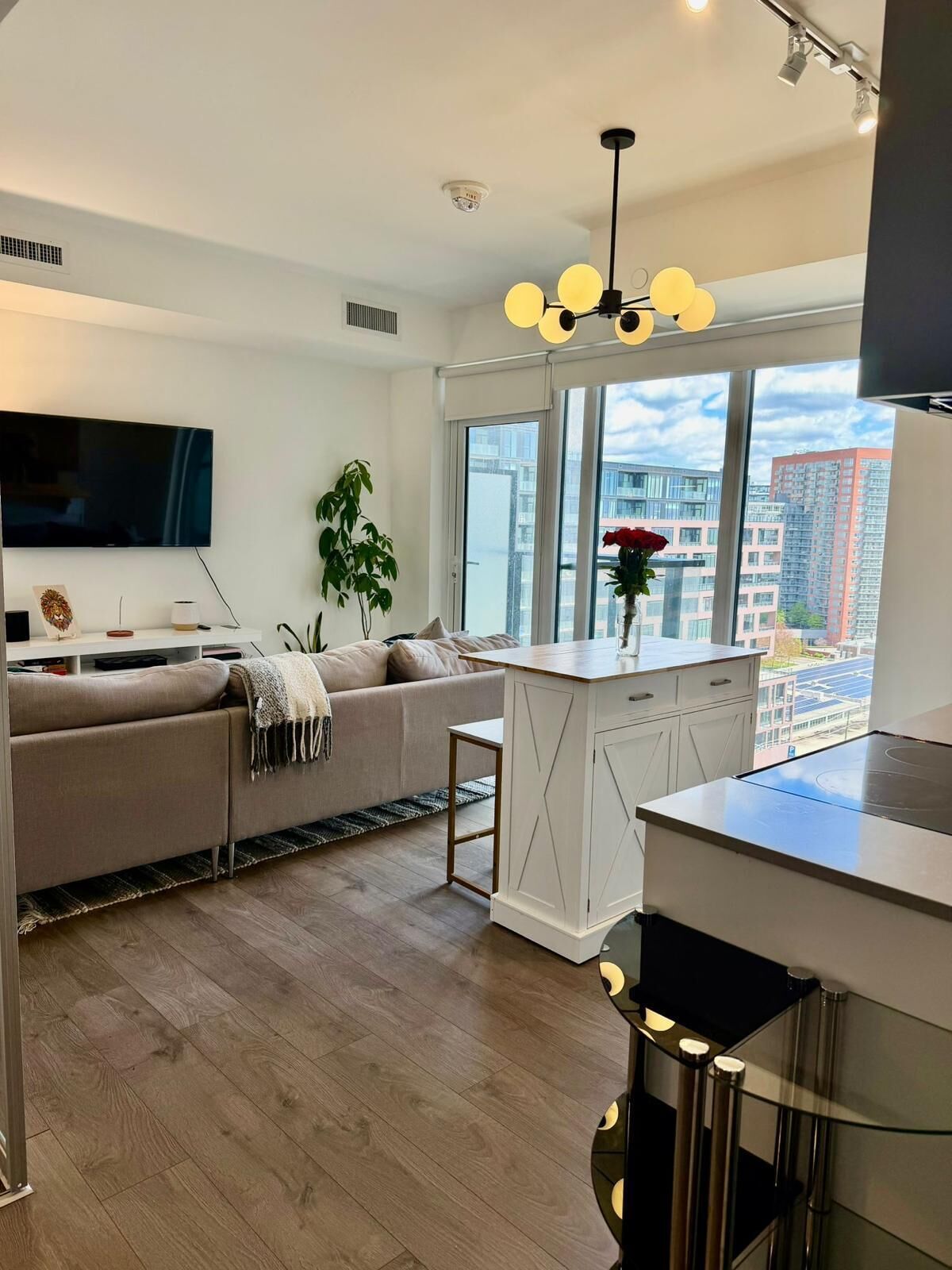 Una sala de estar moderna con un sofá, un televisor de pantalla plana y una zona de comedor con una isla de cocina.