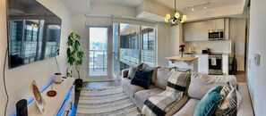 Eine moderne Wohnung mit Wohnzimmer, Küche und großen Schiebeglasfenstern zum Balkon.