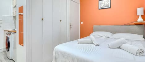 Une chambre d’hôtel avec un lit, une armoire et une petite table avec une lampe.