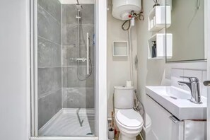 A modern bathroom with a glass-enclosed shower, a white toilet, and a sink with a chrome faucet. - 18-square-meter studio apartment - Bir-Hakeim / 10 minutes from the Eiffel Tower (Paris)