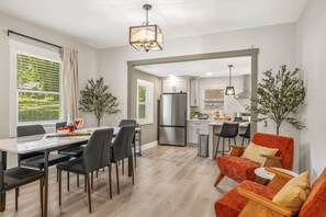 Eine moderne Küche mit Kühlschrank, ein Essbereich mit Tisch und Stühlen sowie ein Wohnbereich mit einer Couch.