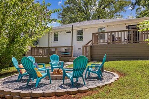 Ein Garten mit Feuerstelle, Sitzgelegenheiten im Freien und einem Haus mit Terrasse.