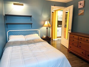 A bedroom with a bed, bedside lamp, dresser, and a view into the kitchen. - Cozy & Quiet 1 Bed/1 Bath Rittenhouse Condo (Philadelphia)