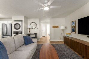 Un salon moderne avec un canapé, une table basse et un téléviseur à écran plat.