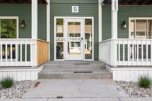 Un bâtiment à l’extérieur vert, avec des balustrades blanches et un panneau portant le chiffre « 5 » au-dessus de l’entrée.