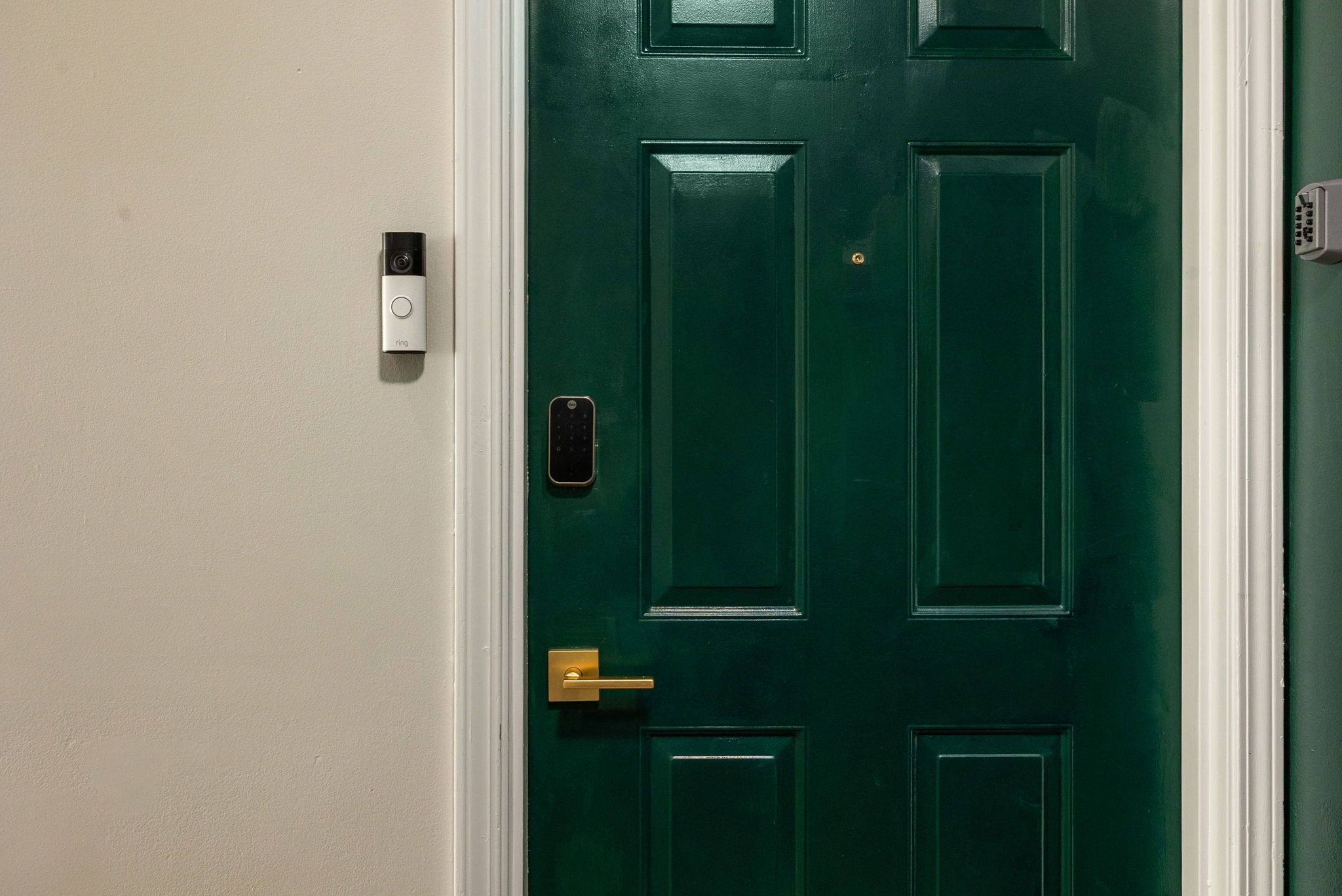 Une porte verte dotée d’un clavier pour l’ouverture, d’une sonnette et d’une poignée dorée.