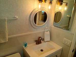 A bathroom with a sink, mirror, towel, and patterned wall. - Unit 117 - Comfy Island Treasure (Ground Floor) (Treasure Island)