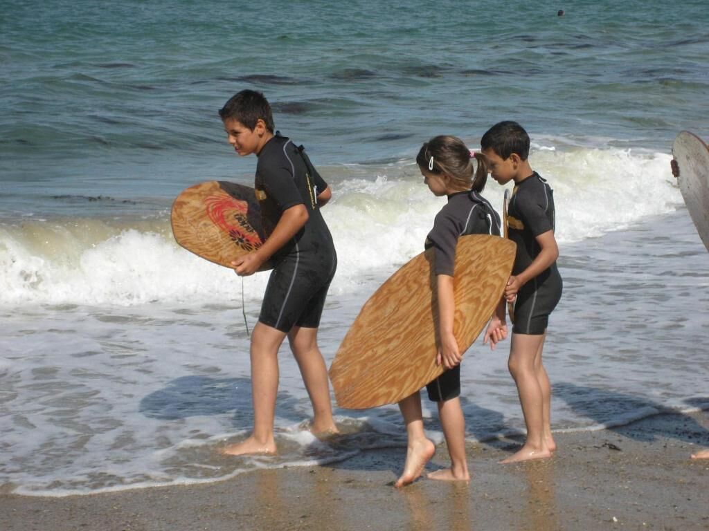 Tres personas caminando por la playa con tablas de surf.