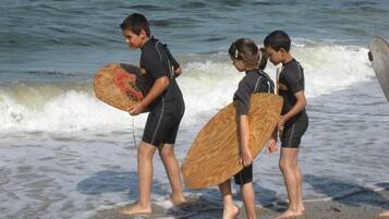 Tres personas caminando por la playa con tablas de surf.