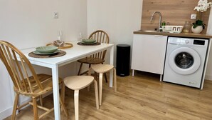 Una cucina compatta con lavatrice, un tavolo da pranzo con sedie e un piccolo angolo lavandino.