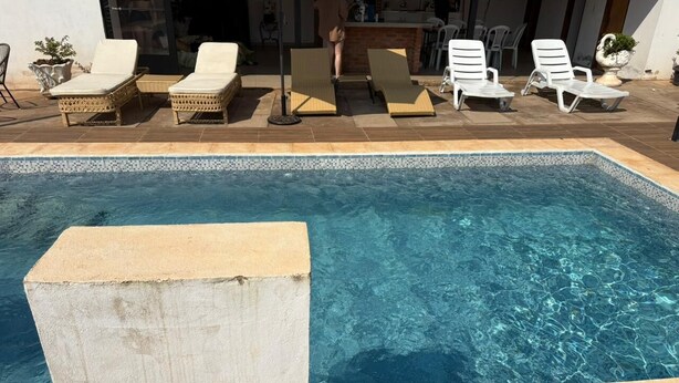 Piscina con sillones de descanso y zona de bar.