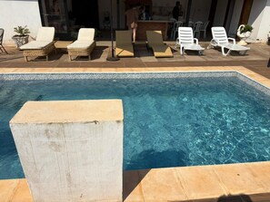A swimming pool with lounge chairs and a bar area.