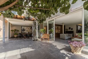 A modern outdoor living area with a dining setup, seating, and potted plants. - Beautiful Villa with a Garden in Downtown San Pedro Tlaquepaque, a "Pueblo Mágico" (San Pedro Tlaquepaque)