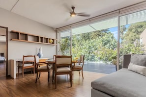 A modern living room with a dining area, large windows, and a ceiling fan. - Beautiful Villa with a Garden in Downtown San Pedro Tlaquepaque, a "Pueblo Mágico" (San Pedro Tlaquepaque)