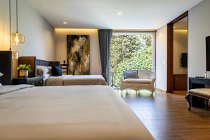 A hotel room with two beds, a sitting area with a chair, a large window with a view of trees, and a painting on the wall. - Beautiful Villa with a Garden in Downtown San Pedro Tlaquepaque, a "Pueblo Mágico" (San Pedro Tlaquepaque)