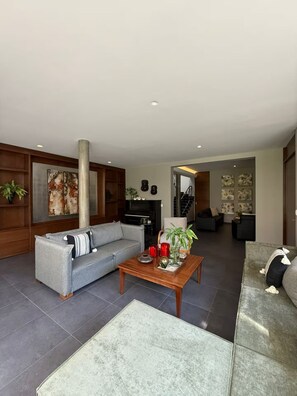 Ein modernes Wohnzimmer mit einem grauen Sofa, einem Holztisch und einem großen abstrakten Gemälde an der Wand.