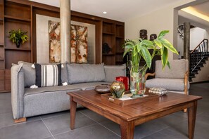 A living room with a grey sofa, a wooden coffee table, and decorative items including a vase with plants and a sculpture. - Beautiful Villa with a Garden in Downtown San Pedro Tlaquepaque, a "Pueblo Mágico" (San Pedro Tlaquepaque)