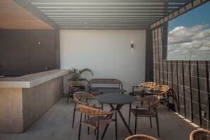 A covered outdoor seating area with a table, chairs, and a bar. - Luxury apartment in Playa del Carmen. (Playa del Carmen)