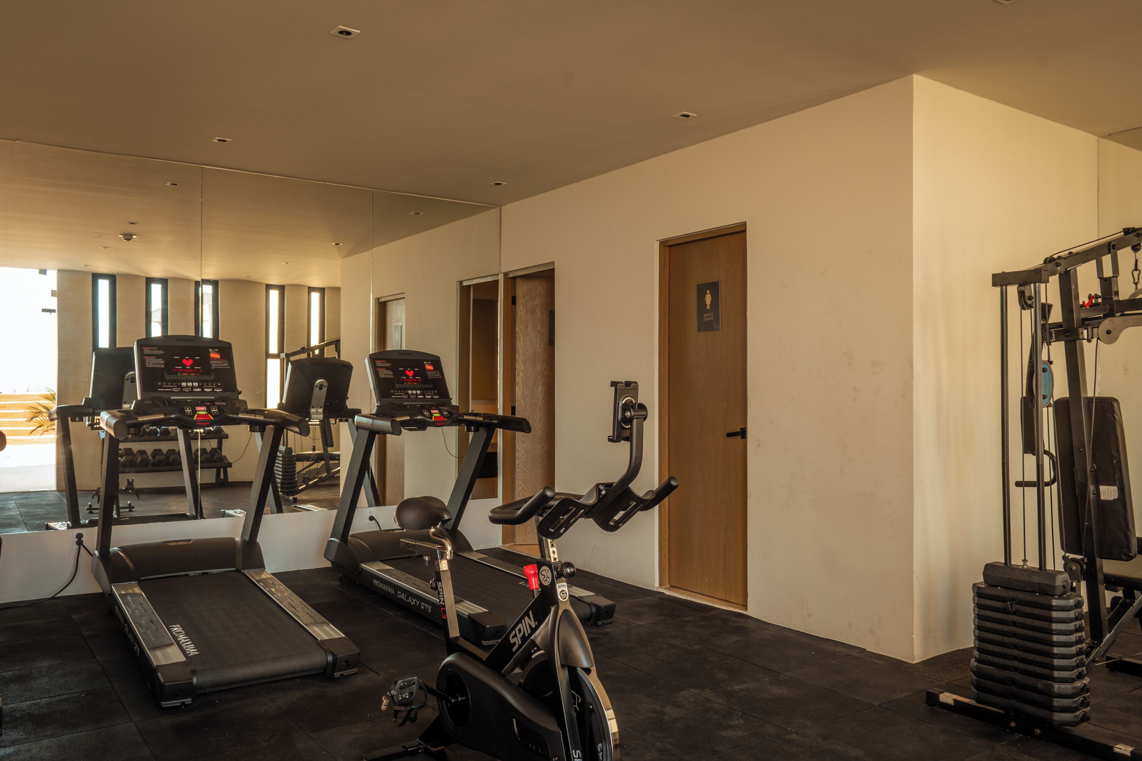 A gym with treadmills, a stationary bike, and weightlifting equipment.