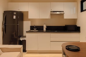 A compact kitchen with a refrigerator, microwave, and a sink. - Luxury apartment in Playa del Carmen. (Playa del Carmen)