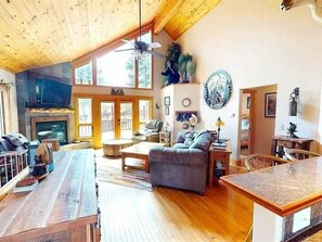 Amplia sala de estar con chimenea, piso de madera y techo alto con vigas a la vista.