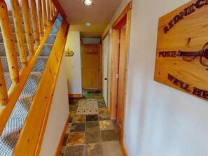 A wooden staircase with a handrail leading to a tiled floor. - Alpen Haus - Cozy Comfort with Garage Parking and Close to Town (Lake City)