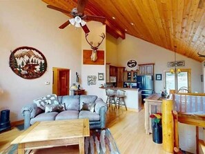 A spacious living area with a sofa, a wooden coffee table, and a ceiling fan.