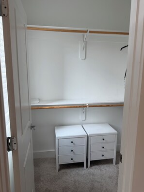 A room with a white door, a white wardrobe with a wooden shelf, and two white bedside tables with drawers. - Starkville MS Luxury Townhome! Perfect for Gameday! 5 minutes to MSU! (Starkville)