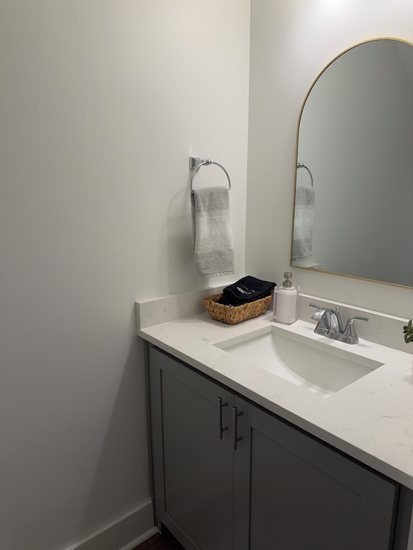A bathroom with a white sink, a mirror, and a towel rack. - Starkville MS Luxury Townhome! Perfect for Gameday! 5 minutes to MSU! (Starkville)