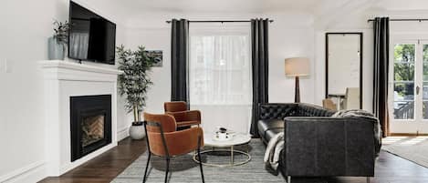 A modern living room with a fireplace, a sofa, a coffee table, and a TV mounted on the wall.