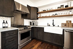 Una cocina moderna con armarios oscuros, electrodomésticos de acero inoxidable y encimera blanca.
