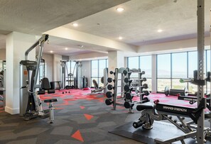 A gym with various exercise equipment, large windows, and a red carpeted floor. - Landing | Beautiful 1BD, Gym (Draper)