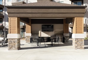 An outdoor patio with a grill, seating, and a flat-screen TV. - Landing | Beautiful 1BD, Gym (Draper)