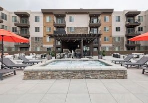 A rooftop pool area with lounge chairs, a hot tub, and outdoor seating. - Landing | Beautiful 1BD, Gym (Draper)