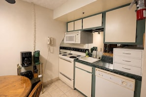 A compact kitchen with a stove, microwave, and a coffee maker on a glass shelf. - SC 2207 | Mountain Summer Escape with Refreshing Pool Access (Snowshoe)